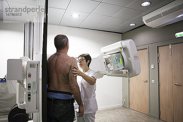 Reportage in einem Radiologiezentrum in Haute-Savoie  Frankreich. Ein Techniker positioniert einen Patienten für eine Röntgenaufnahme des Schlüsselbeins.
