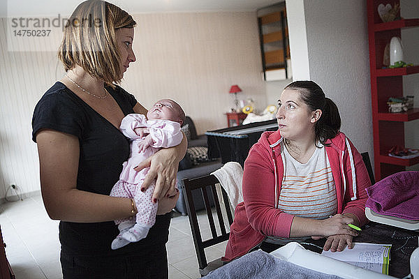 Reportage über eine unabhängige Hebamme bei Hausbesuchen nach der Geburt. Die Hebamme füllt die Krankenakte des Babys aus.