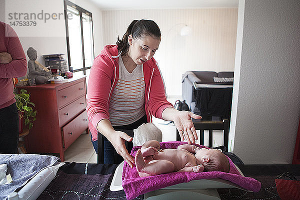 Reportage über eine unabhängige Hebamme bei Hausbesuchen nach der Geburt. Die Hebamme wiegt das neugeborene Baby.