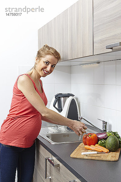 Eine schwangere Frau wäscht Gemüse.