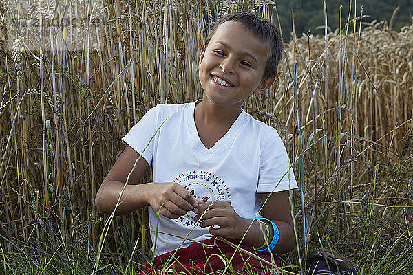9-jähriger Junge lacht in einem Weizenfeld.