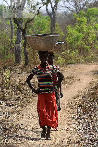 Afrikanische Mädchen holen Wasser mit einem Eimer.
