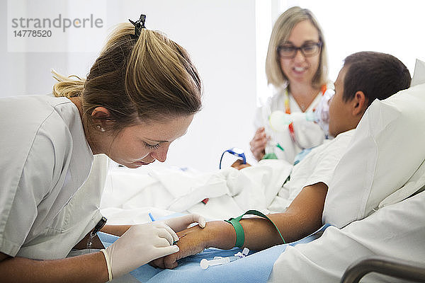 Reportage aus der pädiatrischen Abteilung eines Krankenhauses in Haute-Savoie  Frankreich. Eine Krankenschwester legt einen Katheter  während eine andere eine Maske hält  die Nitronox (eine Mischung aus Gas und Luft) abgibt.
