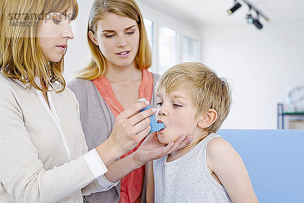 Arzt informiert eine Mutter über die Verwendung eines Bronchodilatators.