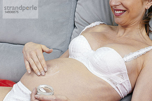 Schwangere Frau beim Eincremen ihres Bauches.
