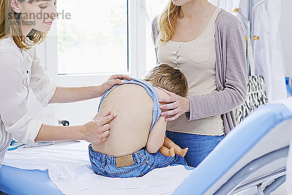 Ein Arzt untersucht den Rücken eines Kindes.