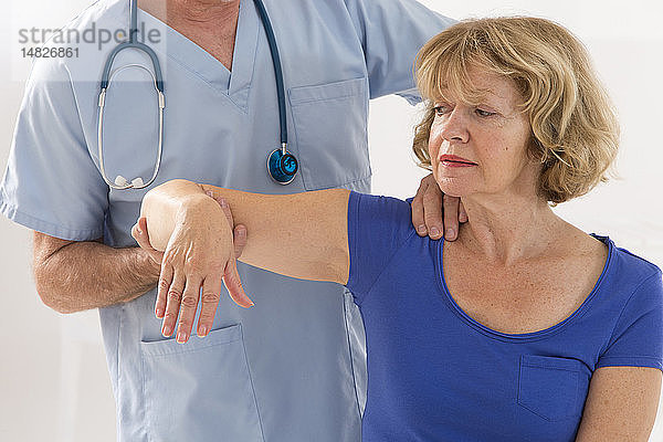Ein Arzt untersucht die Schulter eines Patienten.