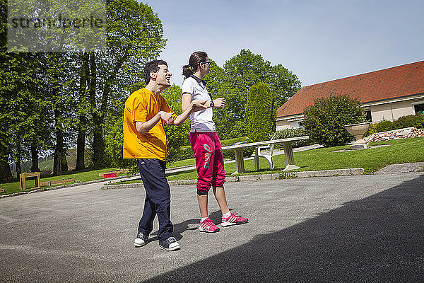 Reportage über einen Sportlehrer  der sich auf angepasste körperliche Aktivitäten in einem speziellen Pflegeheim für Erwachsene mit Mehrfachbehinderungen in Frankreich spezialisiert hat. Der Sportlehrer hilft einem jungen Mann beim Gehen. Wissenschaft und Technik der körperlichen und sportlichen Aktivitäten