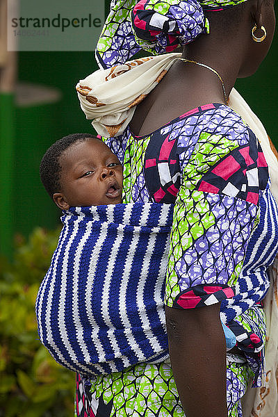 Afrikanische Frau  die ihr Baby auf dem Rücken trägt.