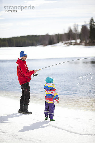 Vater mit Kind beim Fischen im Winter