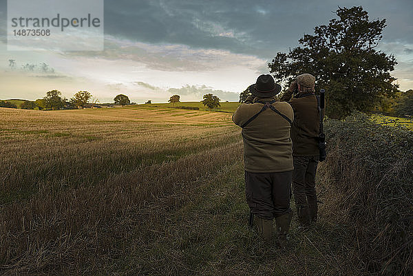 Zwei Jäger schauen auf ein Feld