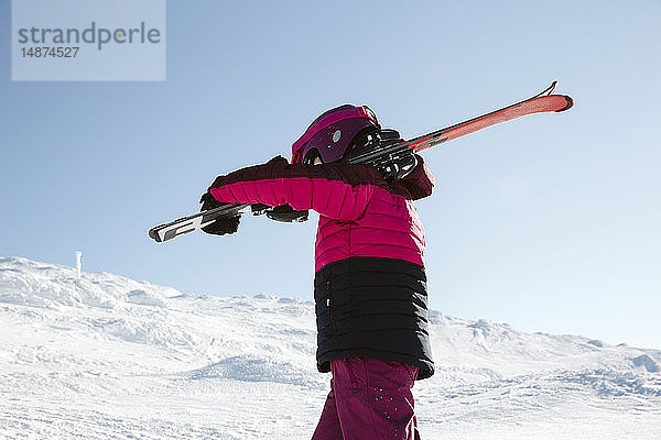 Mädchen trägt Skier in den Bergen