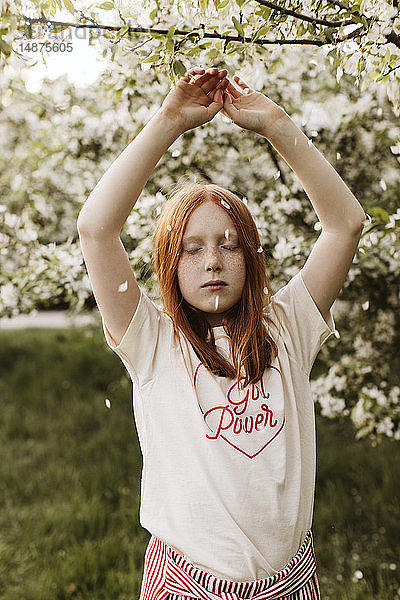 Rothaarige Teenagerin posiert im Obstgarten