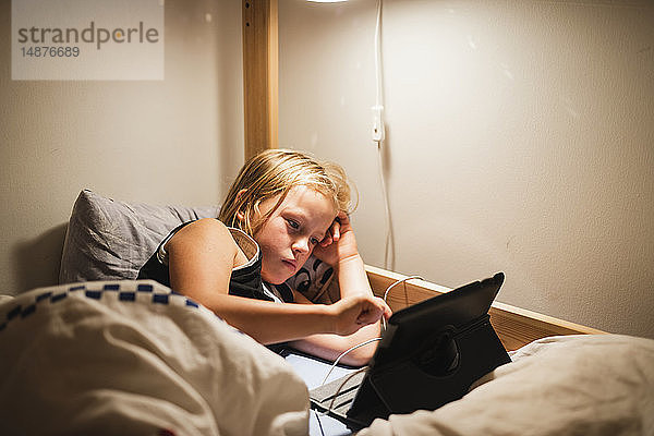 Mädchen mit digitalem Tablet auf dem Bett