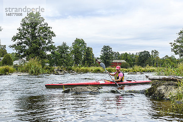 Mann fährt Kajak auf dem Fluss