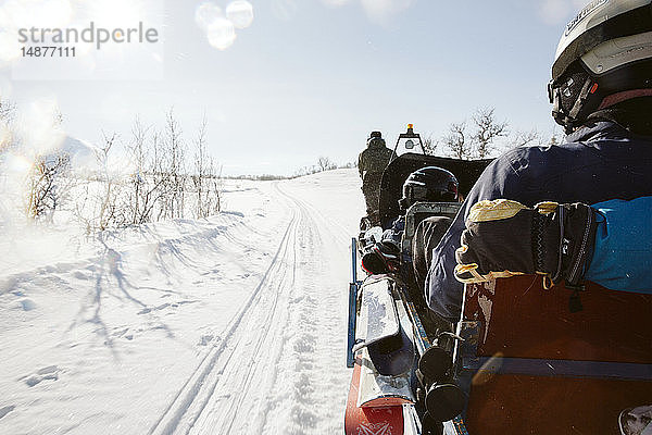 Skifahrer  die mit einem Schneefahrzeug in den Bergen unterwegs sind