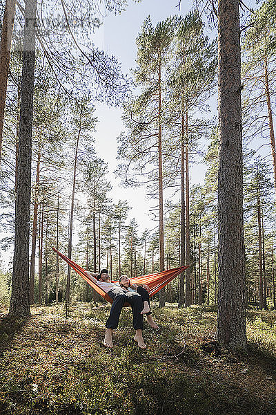 Junges Paar liegt in Hängematte im Wald