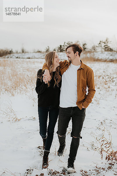 Glückliches Paar geniesst Spaziergang im verschneiten Feld