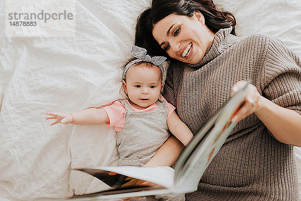 Mutter liest mit der kleinen Tochter im Bett