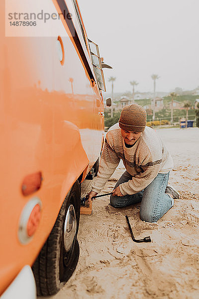 Junger Mann beim Entfernen eines platten Reifens an einem Wohnmobil am Strand  Jalama  Kalifornien  USA