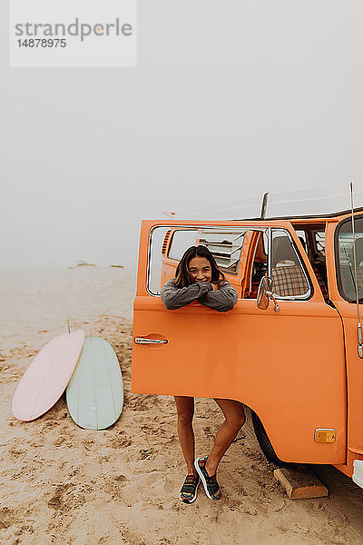 Junge Frau  die sich am Fenster eines Wohnmobils am Strand anlehnt  Porträt  Jalama  Kalifornien  USA