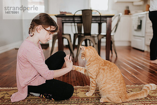 Mädchen spielt zu Hause mit Katze