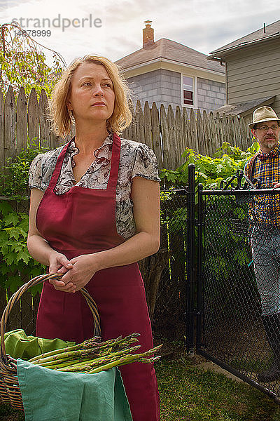 Frau mit Spargelkorb und Ehemann abgelenkt im Garten