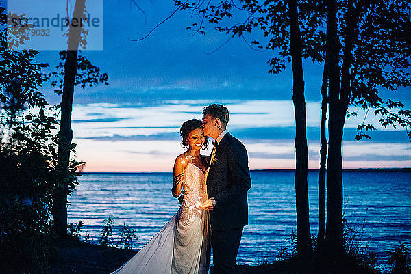 Romantisches Brautpaar mit Wunderkerzen am Seeufer in der Abenddämmerung  Ontariosee  Toronto  Kanada