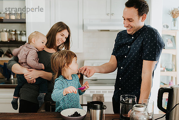 Paar mittlerer Erwachsener mit Kleinkind-Tochter und Baby-Sohn am Küchentisch
