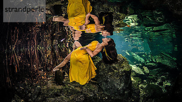 Frau in gelbem Kleid schwimmt unter Wasser  Cenote  Quintana Roo  Mexiko