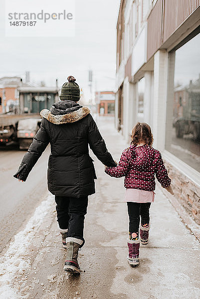 Mutter und Tochter gehen im Winter am Geschäft vorbei