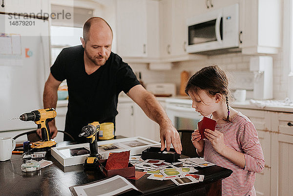 Mädchen hilft Vater beim Ordnen der Karten in der Küchenbox