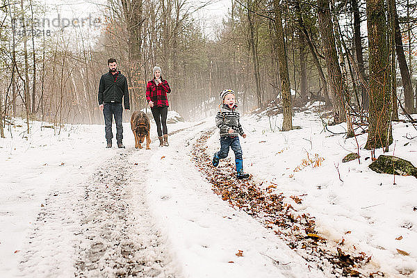 Familie mit Haushund auf Spaziergang in Schneelandschaft