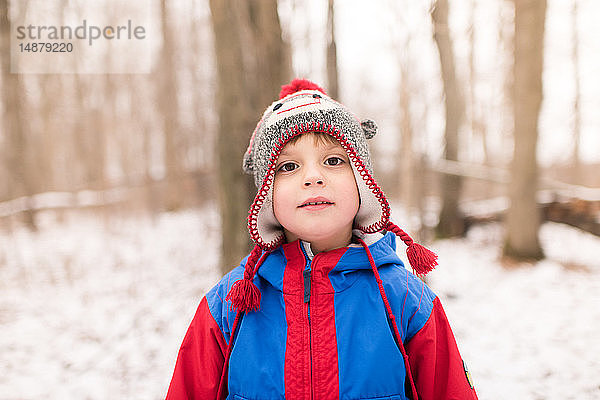 Junge mit Strickmütze durch verschneiten Wald  Porträt