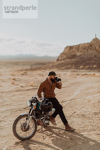 Motorradfahrer  der sein Getränk auf einem stationären Fahrrad genießt  Trona Pinnacles  Kalifornien  USA