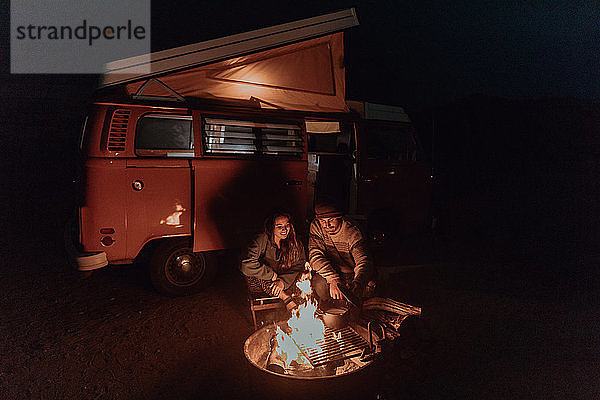 Junges Paar kocht nachts Lagerfeuer mit einem Wohnmobil  Jalama  Kalifornien  USA