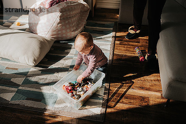 Kleiner Junge sitzt auf dem Wohnzimmerboden und spielt mit Spielzeug