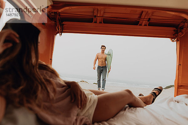 Junge Frau  die auf dem Rücksitz eines Wohnmobils liegt und am Strand auf ihren Surfer-Freund wartet  Jalama  Ventura  Kalifornien  USA