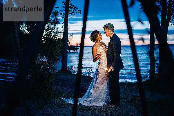Braut und Bräutigam mit Wunderkerzen am Seeufer in der Abenddämmerung  Ontariosee  Toronto  Kanada