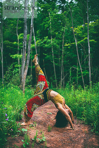 Frau in Rückenbeuge-Pose im Wald