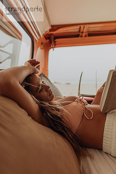 Junge Surferin liest Buch auf dem Rücksitz eines Wohnmobils am Strand  Jalama  Kalifornien  USA