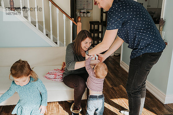 Paar mittlerer Erwachsener mit Baby Junge und weiblichem Kleinkind im Wohnzimmer