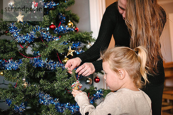 Mutter und Tochter schmücken den Weihnachtsbaum