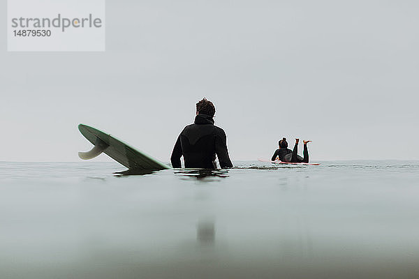Junges Surferpaar auf Surfbrettern bei ruhiger nebliger See  Ventura  Kalifornien  USA