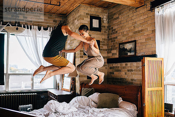 Paar springt auf Bett