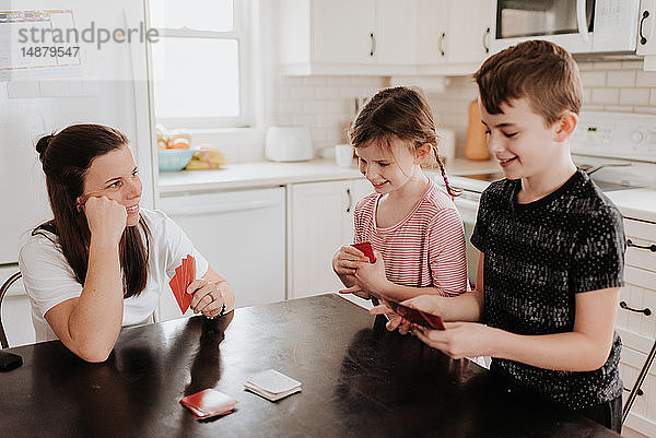 Mutter und Kinder spielen Karten in der Küche
