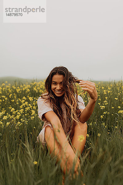 Junge Frau im gelben Wildblumenfeld sitzend  Porträt  Jalama  Kalifornien  USA