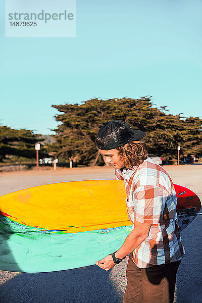 Junger Mann mit Surfbrett am Strand  Morro Bay  Kalifornien  Vereinigte Staaten