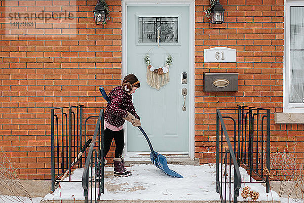 Mädchen schaufelt Schnee auf der Veranda