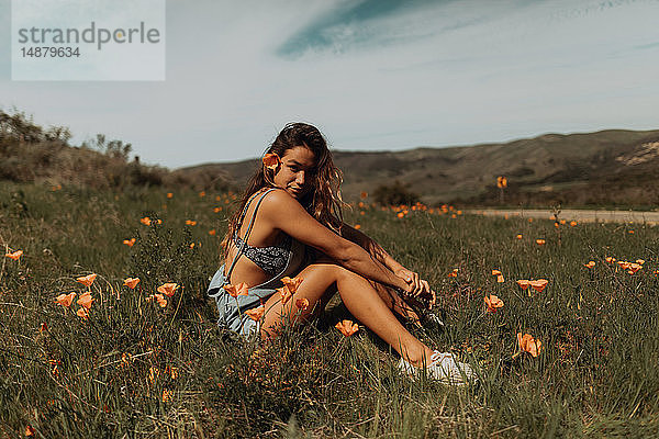 Junge Frau sitzt auf einem Feld mit Wildblumen  Porträt  Jalama  Kalifornien  USA